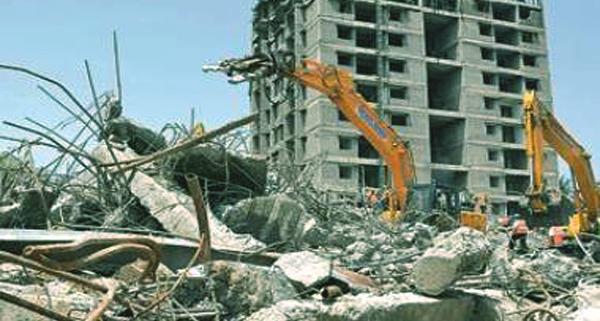 A large building being demolished with a wrecking ball in an dammam area."