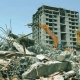 A large building being demolished with a wrecking ball in an dammam area."